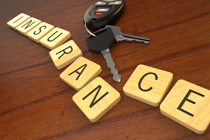 Car keys and key fob displacing letters in word insurance on desk