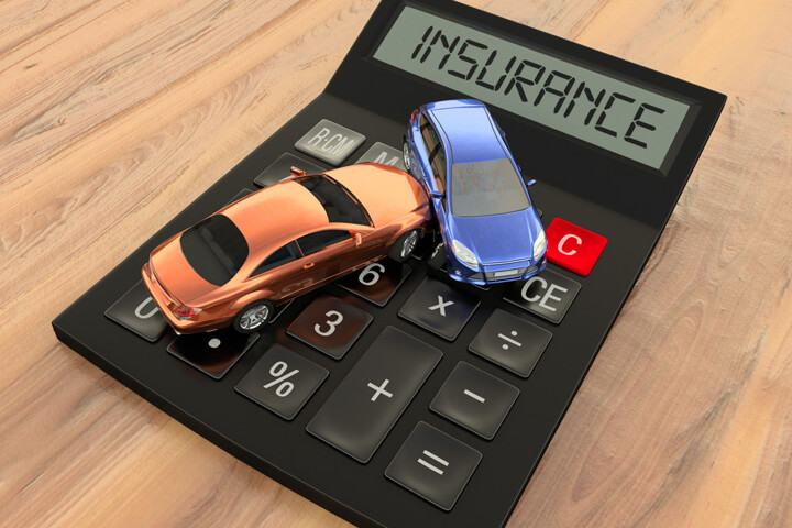 Two car accident on top of black calculator displaying insurance on LCD