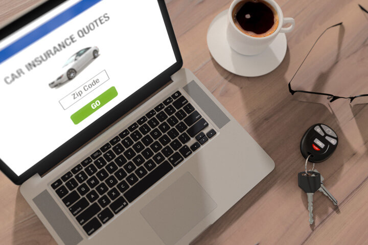Desktop scene with laptop, glasses, car keys, and cup of coffee to illustrate car insurance quotes