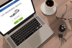 Car insurance quotes on laptop Desktop scene with laptop, glasses, car keys, and cup of coffee to illustrate car insurance quotes