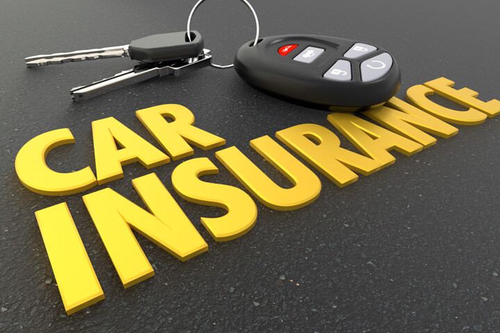 Auto insurance concept image showing car keys and key fob resting on shiny car insurance text