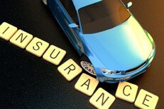Concept image of blue car at sunset skidding through insurance letters on asphalt