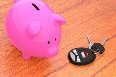 Piggy bank and keys on desk Pink piggy bank on desk next to car keys and key fob