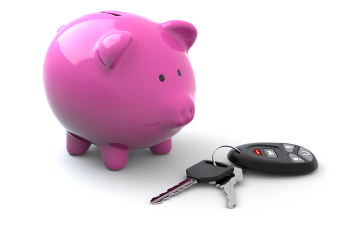 Pink piggy bank next to car keys and clicker isolated on white background