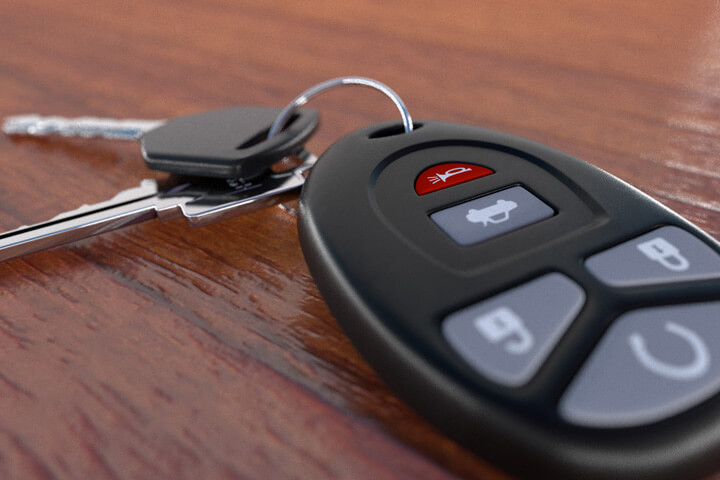 Closeup image of car keys and key fob on wooden desk