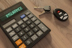 Car keys with insurance calculator on wood desk