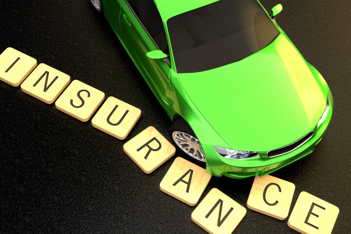 Green sports car sliding and displacing wooden insurance text letters