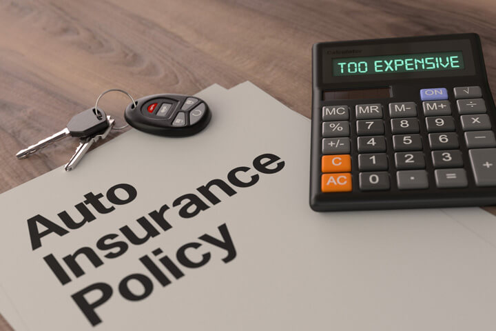 Auto insurance policy with car keys on desk with calculator reading Too Expensive
