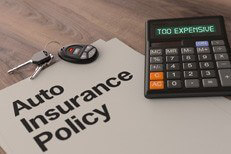 Auto insurance too expensive Auto insurance policy with car keys on desk with calculator reading Too Expensive
