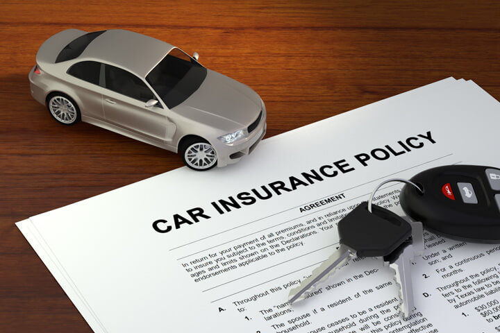 Car insurance policy on desk with small toy car and car keys
