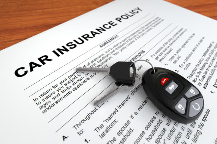 Car insurance policy on desk with car keys and key fob