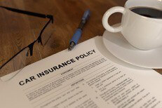 Car insurance policy with coffee Car insurance policy on desk with coffee, glasses, and pen