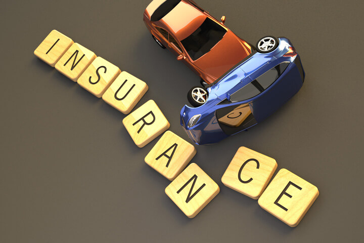 Two car rollover accident sliding through wood insurance letters on dark background