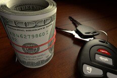 Money roll with car keys Roll of one hundred dollar bills wrapped in rubber bank with car keys on wood table