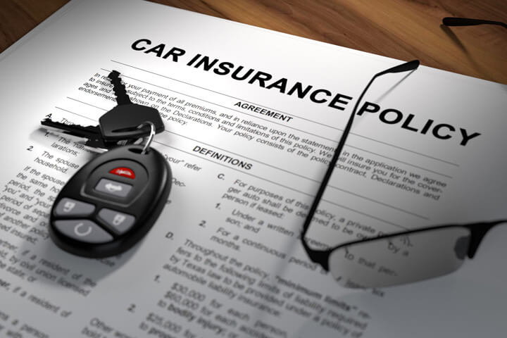 Car insurance policy spotlighted on desk with car keys and glasses