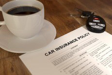 Car insurance policy with coffee and keys Cup of coffee, car insurance policy, and car keys on wood table