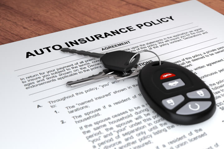 Auto insurance policy and car keys on wood table