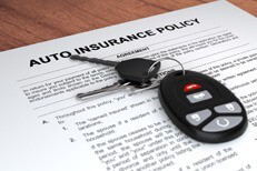 Auto insurance policy with keys on table Auto insurance policy and car keys on wood table