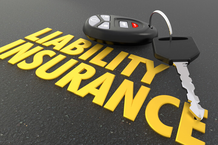 Liability insurance words on asphalt with car keys and key fob
