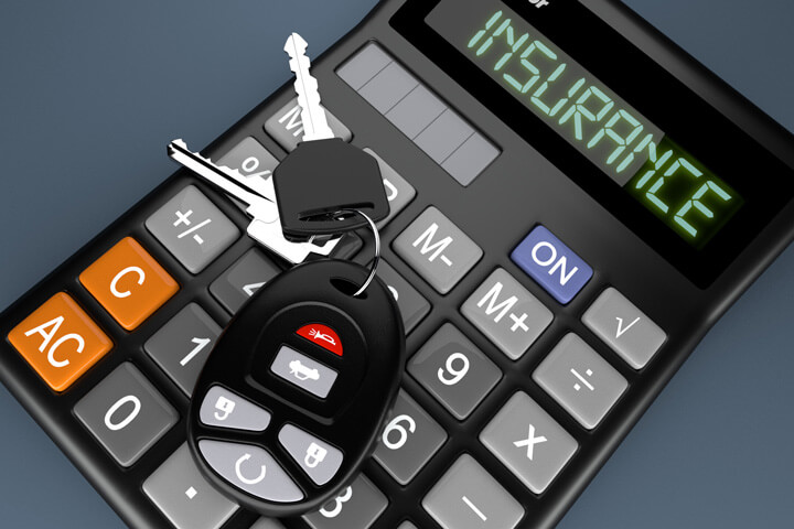 Car keys and key fob on top of calculator reading Insurance on grey background
