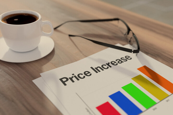 Price increase chart on desk with cup of coffee and glasses