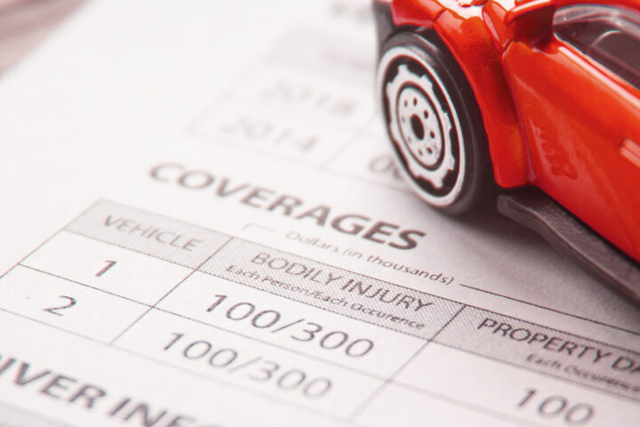 Close up photo of car insurance policy coverages with red toy car
