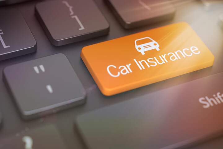 Dark keyboard with large orange Car Insurance key with car icon and corner lens flare effect