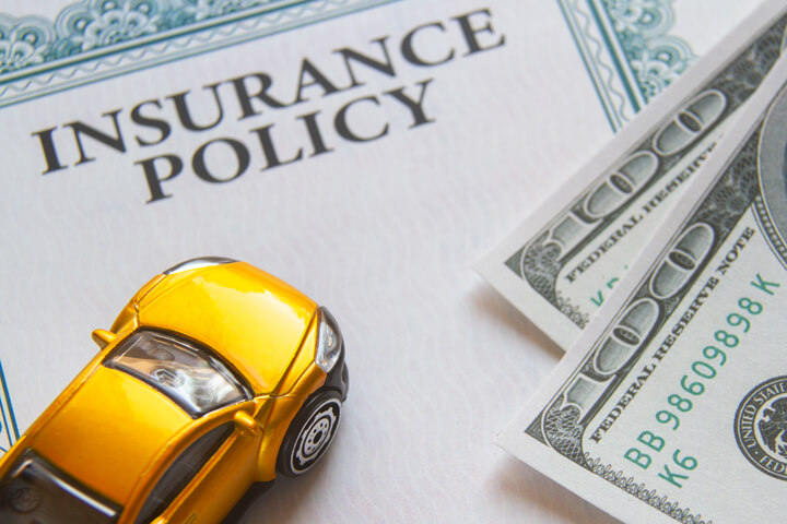 Yellow toy car on insurance policy with two 100 dollar bills car insurance concept