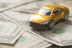 Small car on random bills Small yellow car on randomly assorted one dollar bills