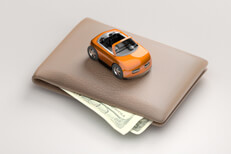 Toy car on top of wallet white background Toy car sitting on top of wallet with corners of bills sticking out from wallet white background
