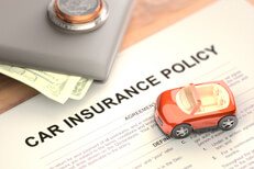 Toy car and wallet on car insurance policy Toy car and wallet with money sitting on paper car insurance policy