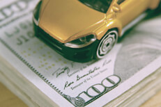 Diagonal car on stack of cash Toy car on stack of one hundred dollar bills