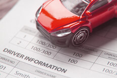 Toy car on top of auto insurance policy showing driver information