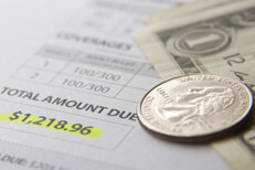 Expensive car insurance Car insurance bill showing total amount due with dollar bills and a quarter