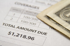 Auto insurance bill with dollars Auto insurance bill showing amount due with two dollar bills