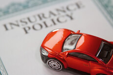 Red car on an insurance policy certificate with focus on the car and short depth of field