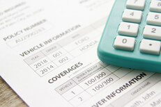 Car insurance coverage calculator Photo of a car insurance policy with a calculator