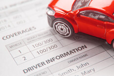 Red toy car on insurance policy Red toy car on auto insurance policy showing coverages and driver information