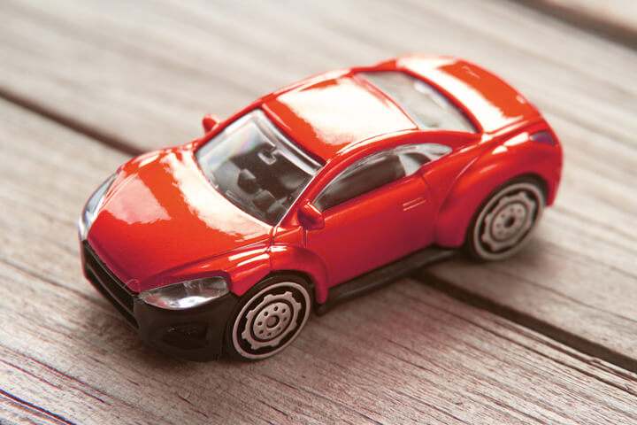 Red toy sports coupe on weathered wood plank background