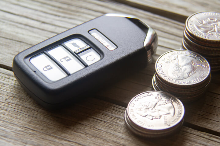 Car insurance cost concept photo of remote entry and stacks of coins