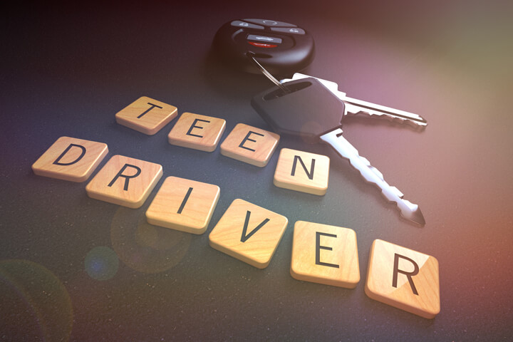 Concept for teen drivers and car insurance with wood letters, car keys, and overlay with lens flare