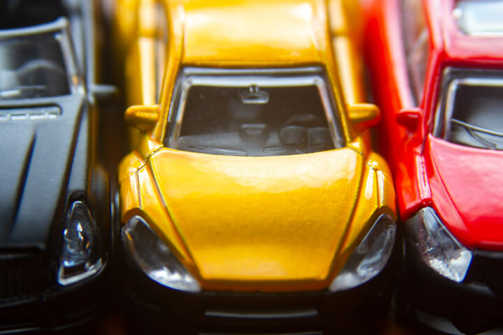 Photo of black, yellow, and red toy cars in a row close up