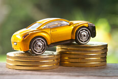 Yellow toy car on coin stacks angled Angled view photo of yellow toy car climbing two stacks of gold coins