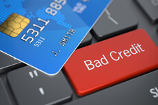 Bad credit keyboard key Bright red Bad Credit key on dark laptop keyboard with blue credit card lying on top