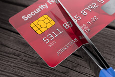 Scissors cutting credit card Top view of scissors cutting through red credit card