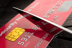 Scissors cutting red credit card Shiny scissors cutting red credit card close up