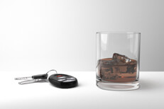 Glass of whiskey and car keys on white Drunk driving concept of glass of bourbon whiskey and car keys on a white studio background