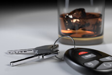 Whiskey glass and car keys on white studio background DUI concept showing whiskey glass and car keys on white studio backdrop