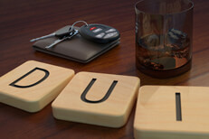 Wood letters spelling DUI Wood letters spell DUI in front of alcoholic drink and wallet with car keys