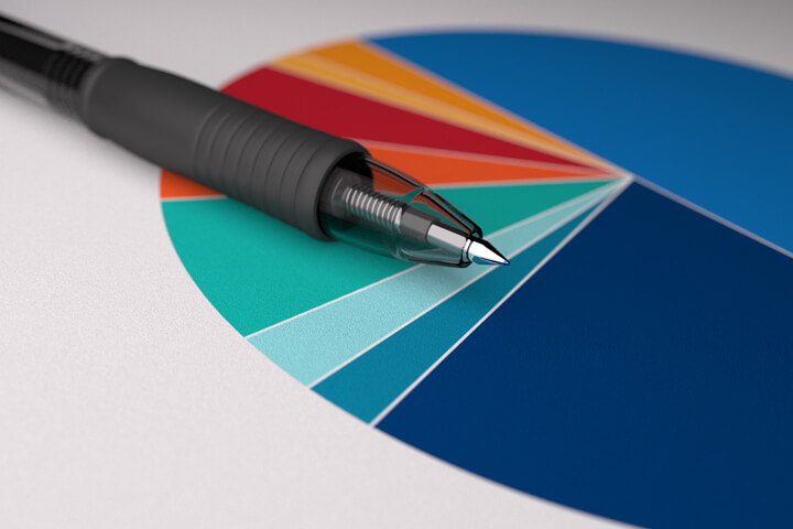 Paper with colorful pie chart with ballpoint pen laying on top